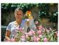 Frau gießt rosa Blumen mit einem Gartenschlauch.