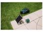 Mähroboter und Solarpanel mit Akku auf Rasen und Pflaster.