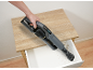Handstaubsauger reinigt eine schmutzige Schublade in einem Holztisch.