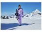Frau in lila Snowboardanzug mit Snowboard auf einem verschneiten Berg.