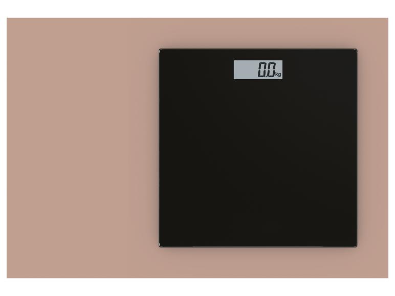 Schwarze digitale Personenwaage mit Anzeige von 0,0 kg auf rosafarbenem Hintergrund.