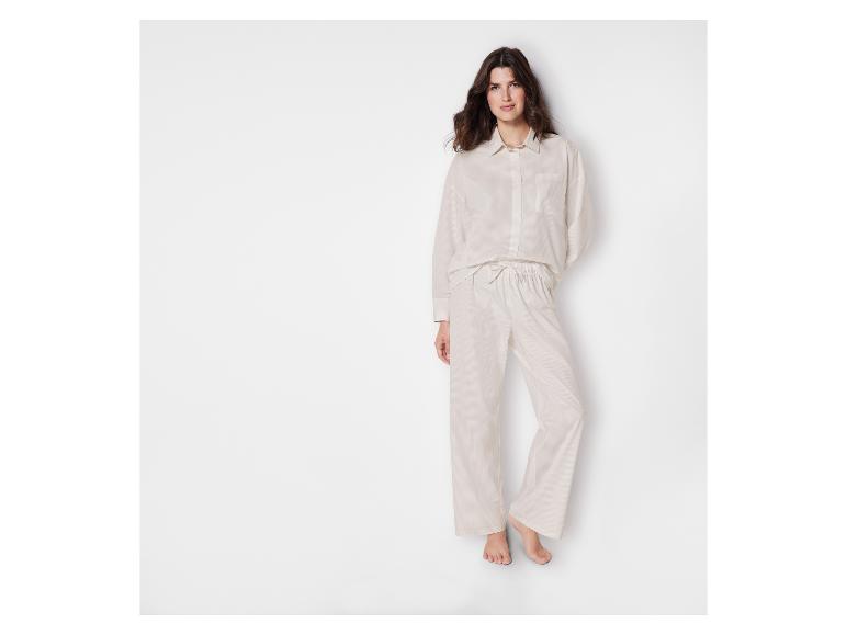 Frau in einem weißen, gestreiften Hemd und einer passenden Hose.