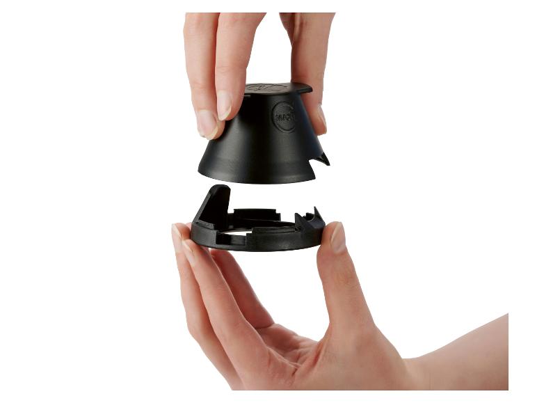 Hände montieren zwei schwarze Kunststoffteile, möglicherweise für ein Küchengerät.