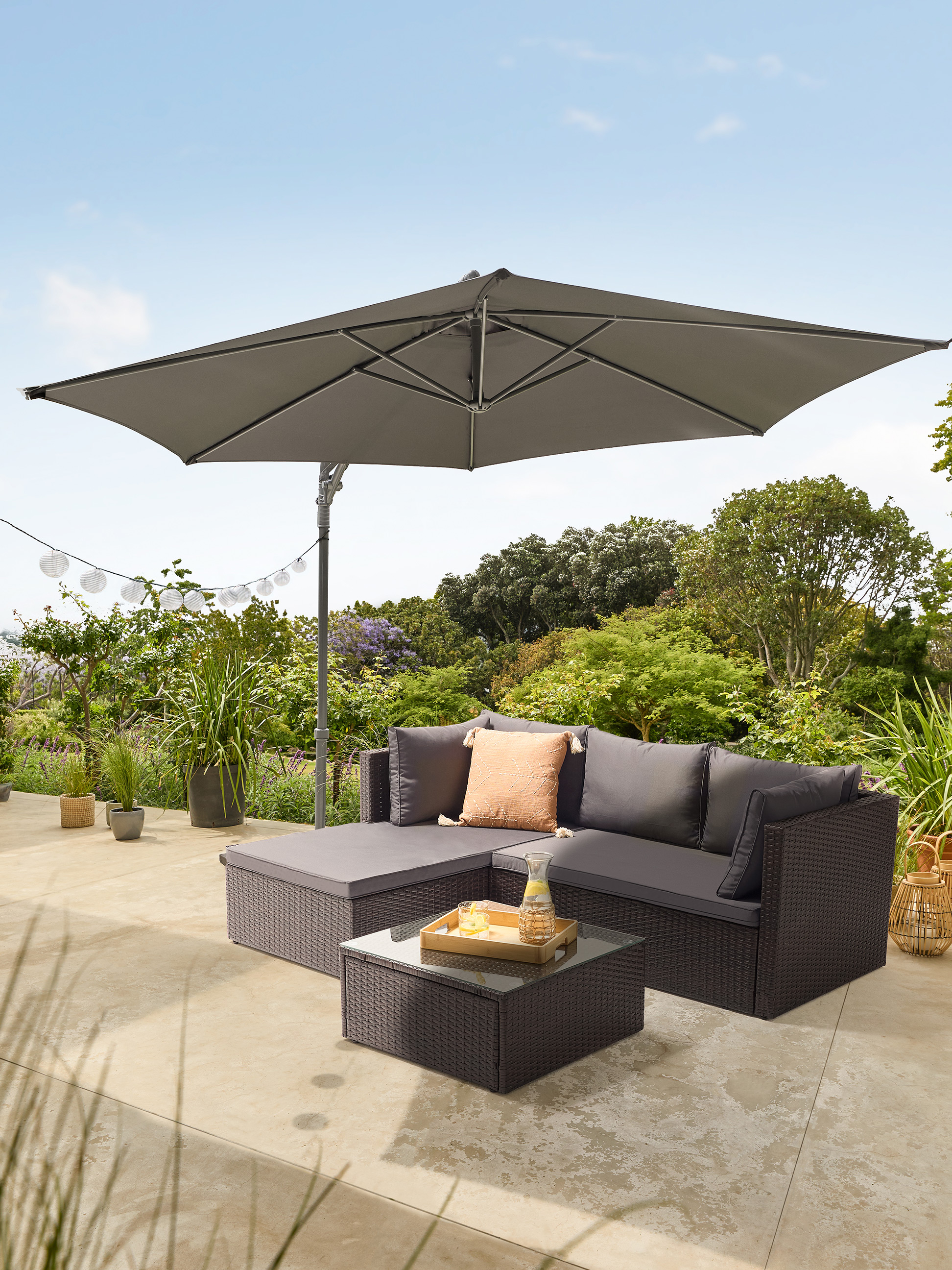 Gartensofa-Set mit Sonnenschirm und Couchtisch auf einer Terrasse.