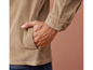 Eine beige Cordjacke mit einer Hand in der Tasche.