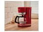 Rote Kaffeemaschine auf einer Küchenarbeitsplatte, mit Keksen und Milch im Hintergrund.