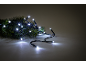 Weiße LED-Lichterkette auf einem Tannenzweig, vor dunklem Hintergrund.