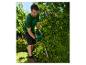 Mann schneidet Hecke mit Heckenschere, Schutzbrille und Handschuhen.