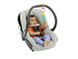 Ein Baby sitzt in einem Autositz und spielt mit einem bunten Ring.