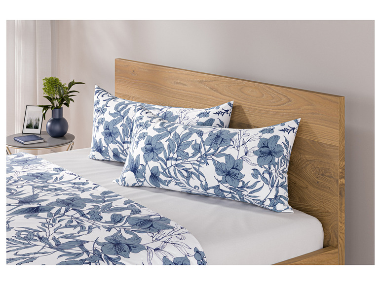 Ein Bett mit einem Holzkopfteil und Bettwäsche mit einem blauen Blumenmuster.
