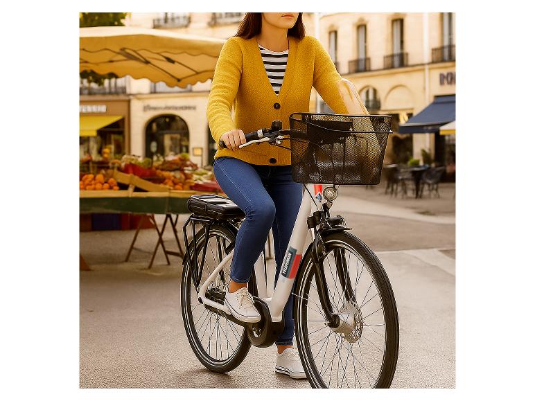 Frau auf einem E-Bike mit Korb, neben einem Obststand.
