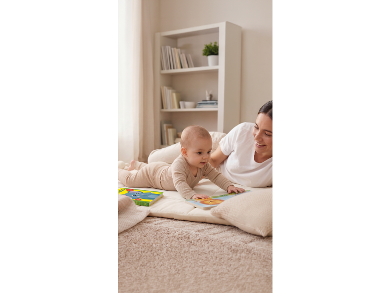 Mutter und Baby spielen mit Bilderbüchern auf einem weichen Teppich.