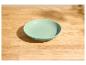 Mintgrüne Schale auf einem hellen Holztisch mit Schatten