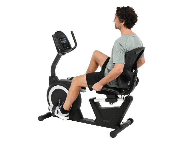 Mann benutzt ein schwarzes Liege-Heimtrainer auf weißem Hintergrund.