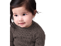 Ein süßes Baby mit dunklem Haar in einem gerippten Pullover.