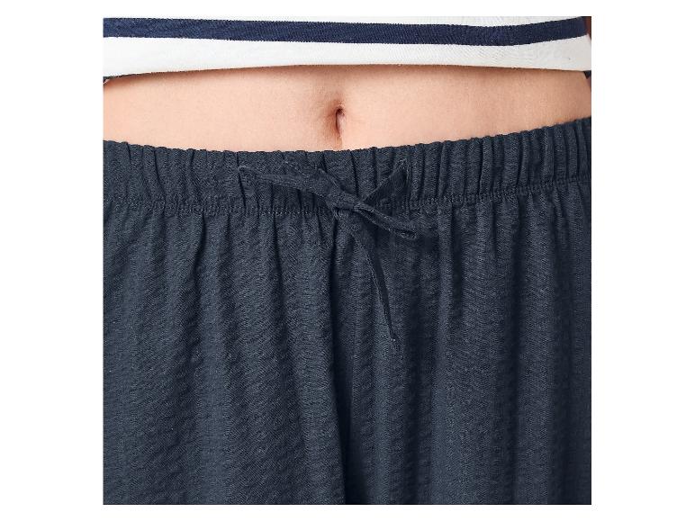 Bauch einer Person in gestreiftem Oberteil und marineblauer Pyjamahose mit Kordelzug.