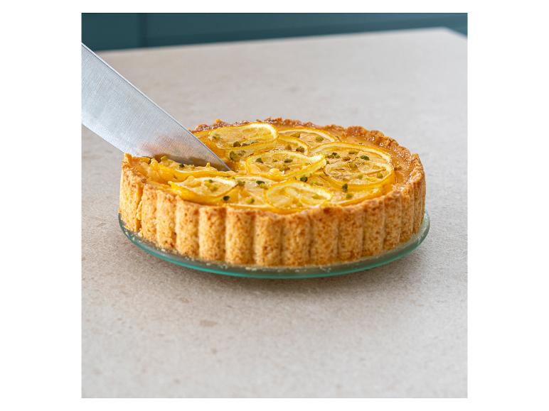 Ein Zitronen-Pistazien-Kuchen wird mit einem Messer geschnitten.