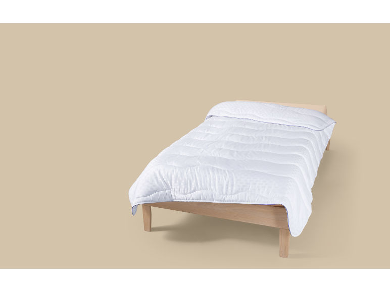 Einzelbett mit weißer Bettdecke auf beigem Hintergrund.