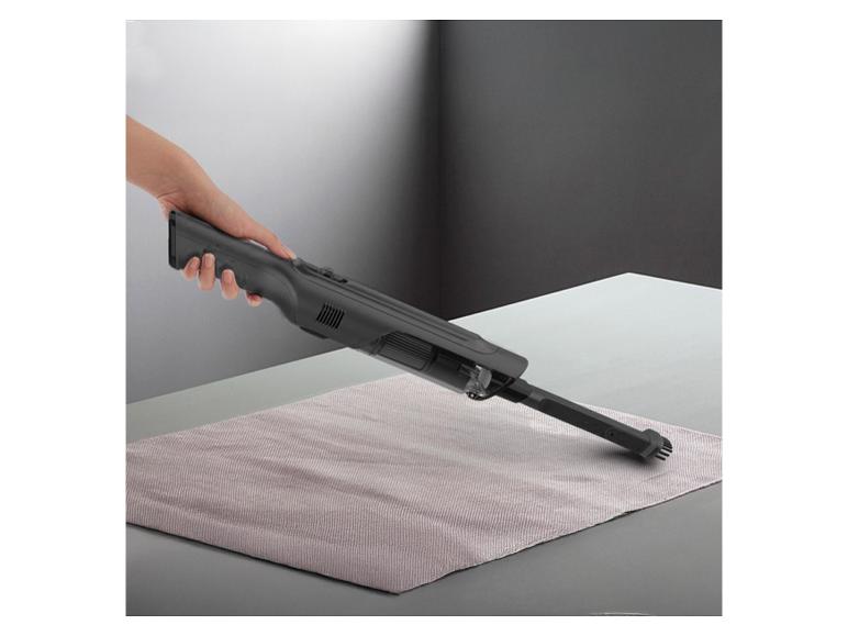 Handstaubsauger reinigt eine Tischdecke.