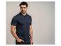 Mann in marineblauem Poloshirt und schwarzer Hose, posiert mit der Hand in der Tasche.