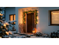 Haustür dekoriert mit einer Weihnachtsgirlande mit Lichtern, Schnee und einer Laterne.