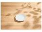 Weiße Untertasse auf einem hellen Holztisch mit Blattschatten.