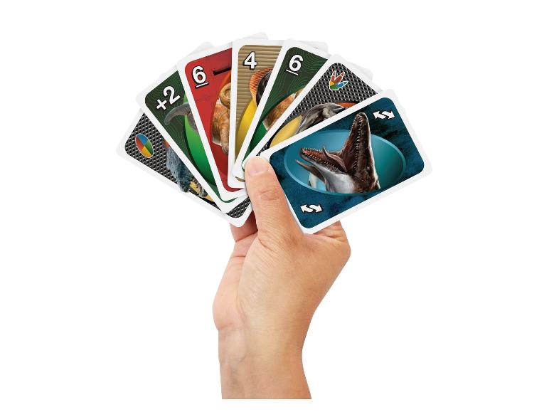 Eine Hand hält ein Set UNO-Spielkarten mit Dinosaurier-Motiv.