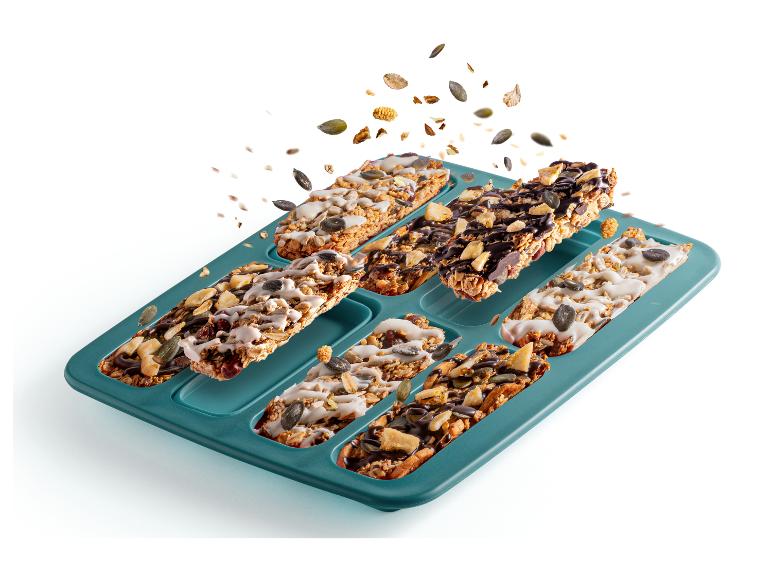 Granola-Riegel in Backform, bestreut mit Nüssen und Samen.