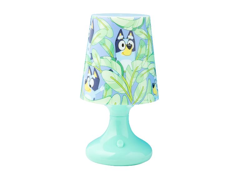 Bluey-Tischlampe mit hellblauem Sockel und Schirm mit Bluey und Bingo zwischen grünen Blättern.