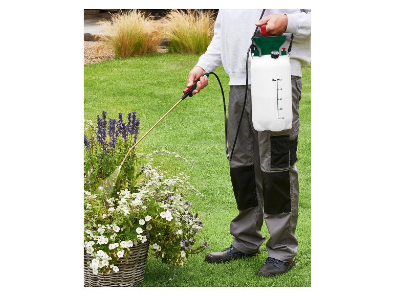 Person besprüht Pflanzen im Garten mit einem schultergetragenen Drucksprühgerät.