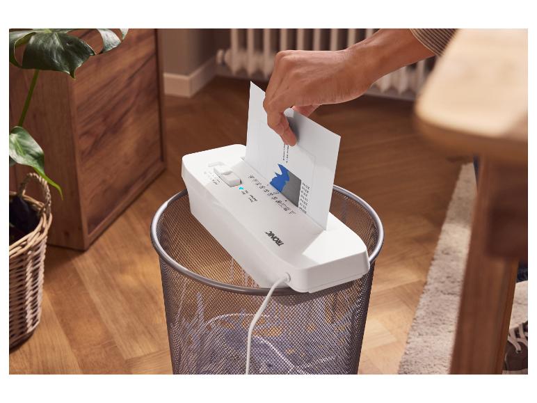 Eine Person schreddert ein Dokument mit einem TRONIC Aktenvernichter über einem Papierkorb.