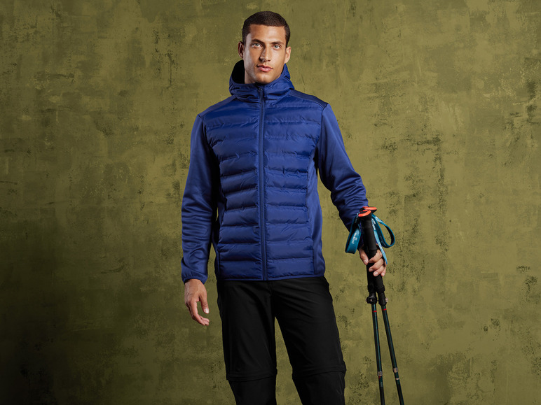 Mann in blauer Jacke mit Kapuze und Wanderstöcken.