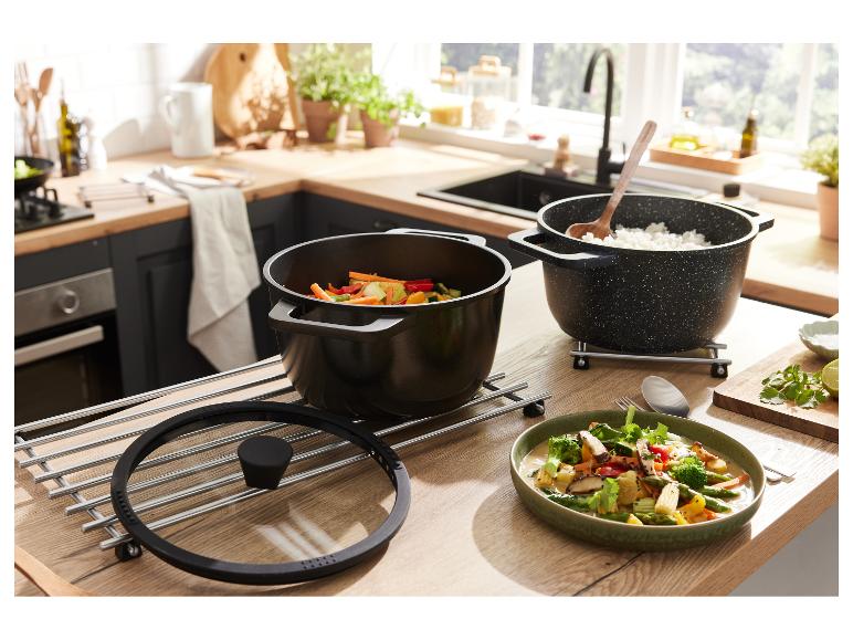 Zwei schwarze Töpfe mit Essen auf einem Holztisch in der Küche.