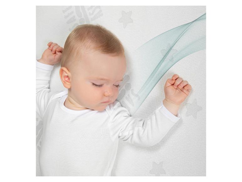 Baby schläft auf einer Matratze mit Sternen- und Wellenmuster.