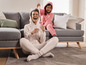 Zwei Frauen in Pyjamas lachen und spielen auf der Couch.