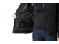 Frau in schwarzer Skijacke und blauer Skihose, zeigt das Innenfutter der Jacke mit Taschen.
