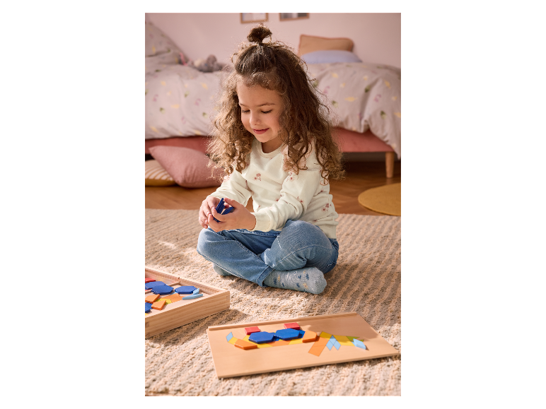 Mädchen spielt mit einem Spiel aus bunten Holzwürfeln.