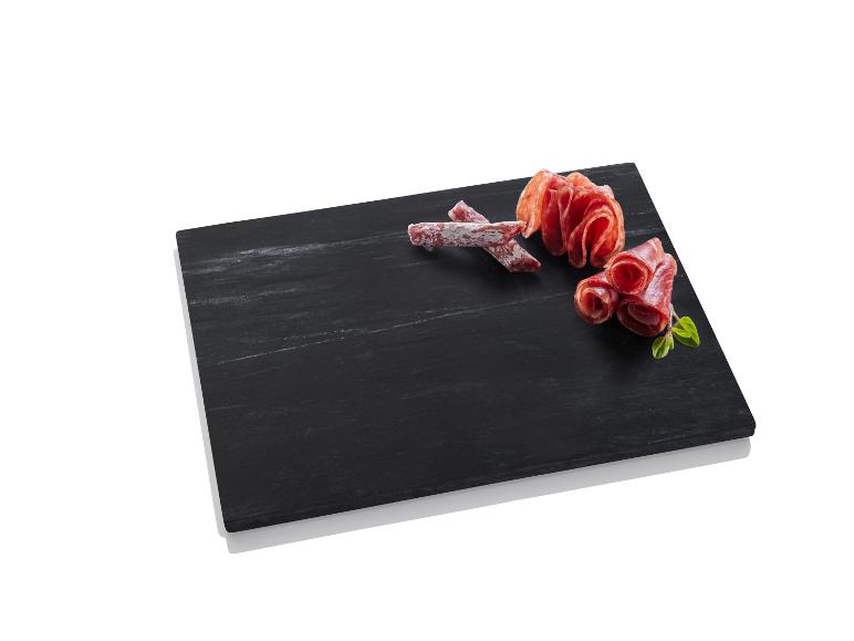 Salami und Wurst auf einem schwarzen Schneidebrett.