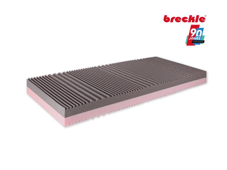 Matratze mit einer grauen Wellenoberfläche und einer rosa Basisschicht, feiert 90 Jahre Familientradition.