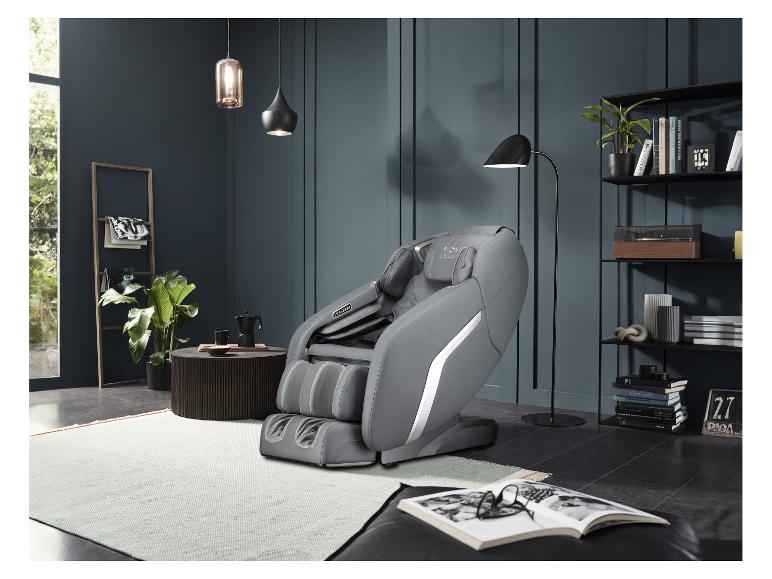 Grauer Massagesessel in modernem Wohnzimmer mit Regalen und Pflanzen.