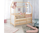 Ein Babybett aus Holz in Form eines Hauses mit rosa Accessoires.