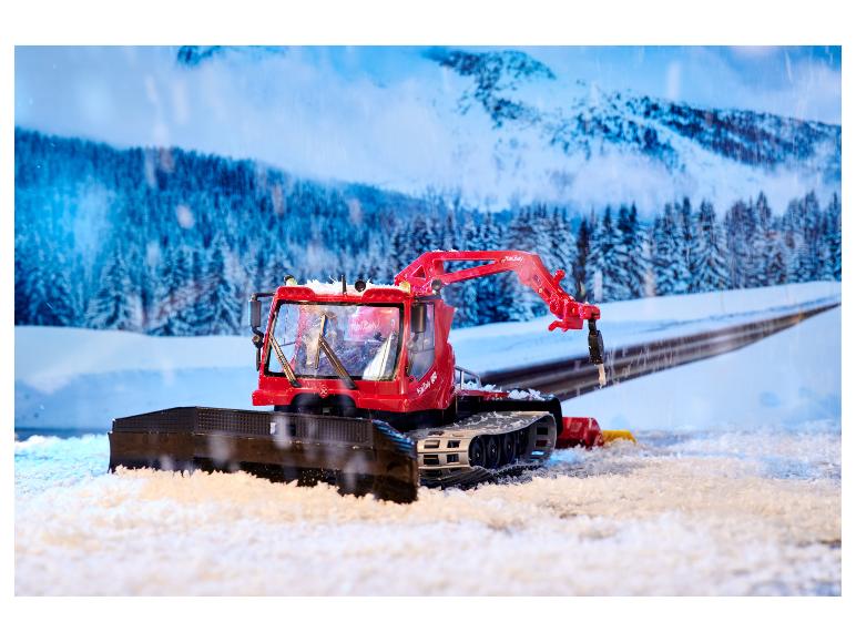 Roter PistenBully 600 Schneepflug mit Schneeschild in Winterlandschaft.