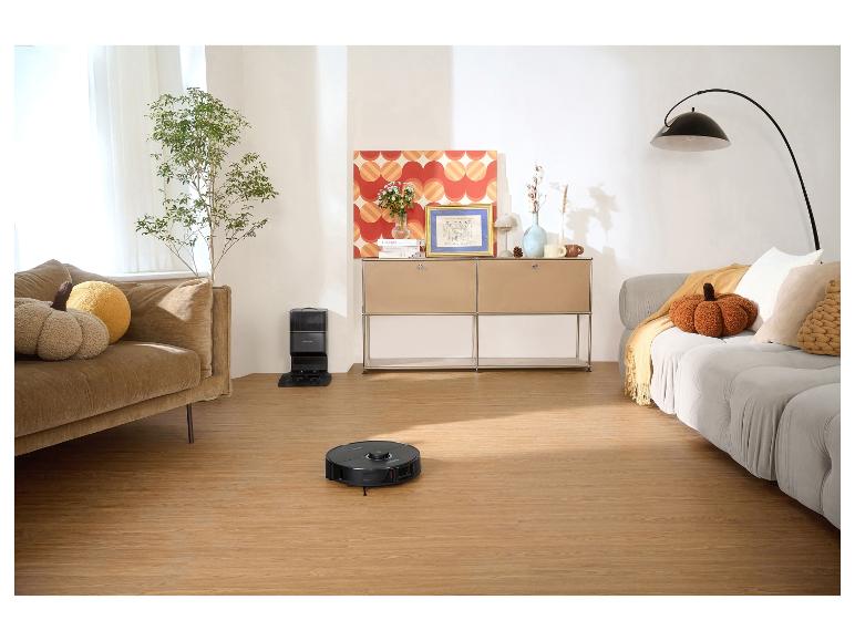 Saugroboter in einem Wohnzimmer mit Sofas und einem Schrank.