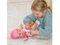 Ein Kind spielt mit einer Babypuppe auf einem Teppich und zieht ihr ein rosa Outfit an.
