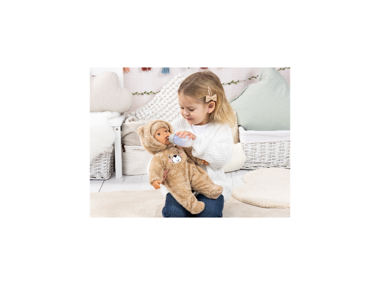 BAYER DESIGN Piccolina Magic Tears Puppe im Bären-Outfit wird von einem Kind mit Fläschchen gefüttert