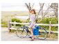Eine Frau mit Hut posiert neben ihrem blauen Beach Rocket Fahrrad.