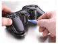 Hände öffnen einen Gamecontroller mit einem blauen Hebelwerkzeug.