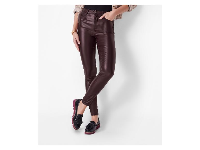 Frau trägt dunkelbraune, beschichtete Skinny Jeans und schwarze Loafer mit Quasten.