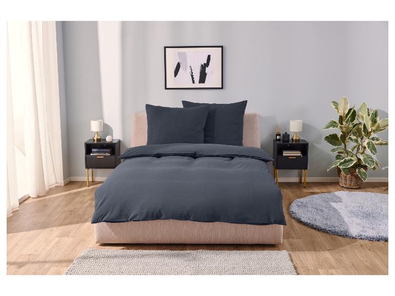 Dunkelblaue Bettwäsche und weicher Teppich in einem modernen Schlafzimmer.