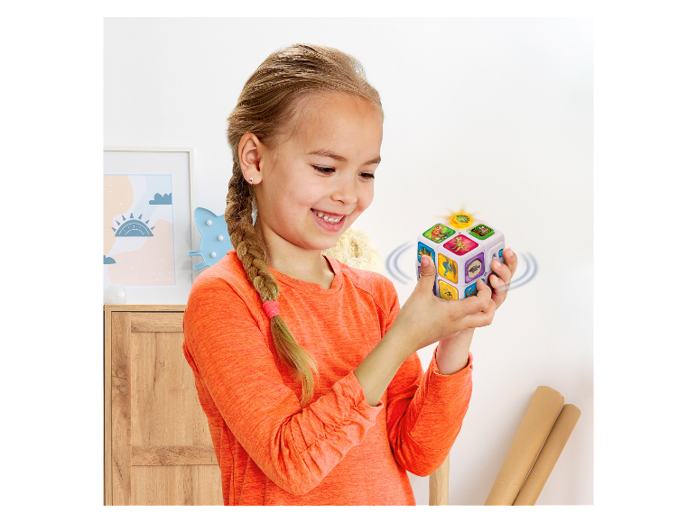 Ein Mädchen spielt mit einem leuchtenden, interaktiven Würfel mit Tiermotiven.